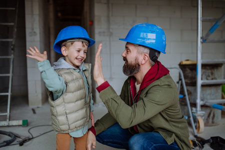 Father and his little son working on their unfinished house.の写真素材