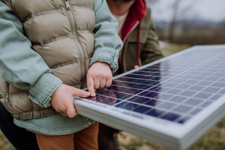 Close-up of father and his little son holding solar panel, in front of their new unfinished house.の写真素材