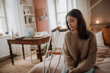 Unhappy girl with broken leg in her room.の写真素材
