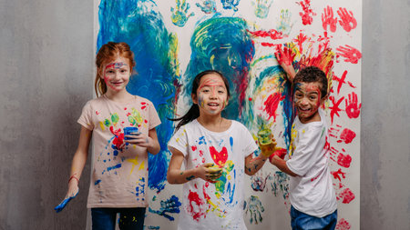 Portrait of happy kids with finger colours and painted t-shirts, studio shoot.