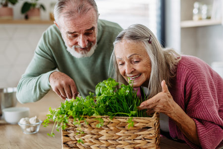 Senior couple smelling fresh herbs during cooking.の写真素材
