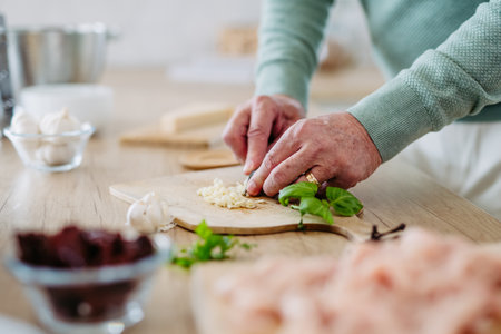 Close up of senior man cutting garlic.の写真素材