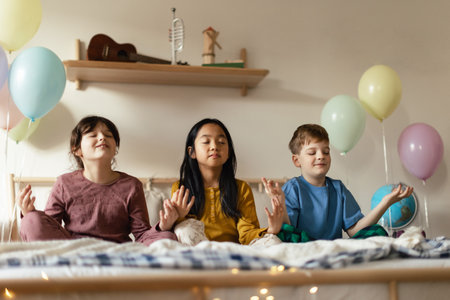 Three happy friends sitting on a bed and mediating.の写真素材