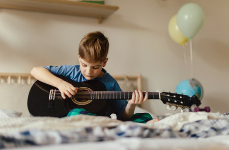 Happy boy playing on the guitar in his room.の写真素材