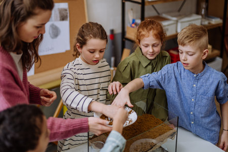 Young teacher making little greenhouse with their pupils, learning them about planting.