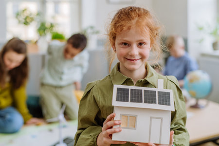 Little girl posing with model of house with solar system during a school lesson.の写真素材