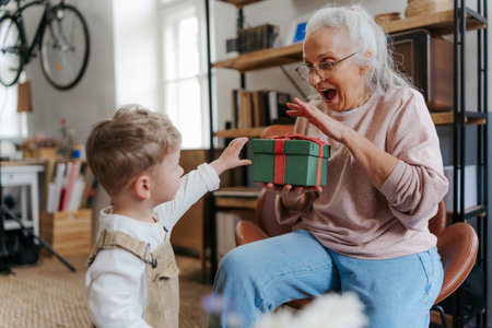 Grandmother giving gift to her little grandson.の写真素材