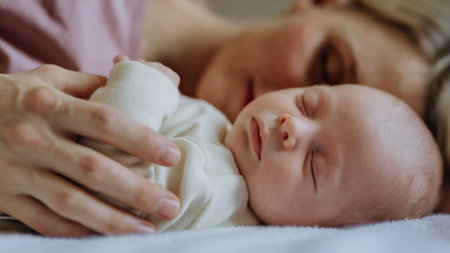 Mother cuddling with her newborn baby in their bed.の写真素材