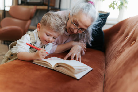 Grandmother drawing in a notepad with her little grandson.の写真素材