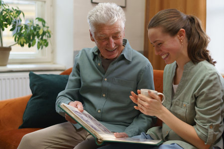 Senior man with his grandaughter looking family photo album.の写真素材