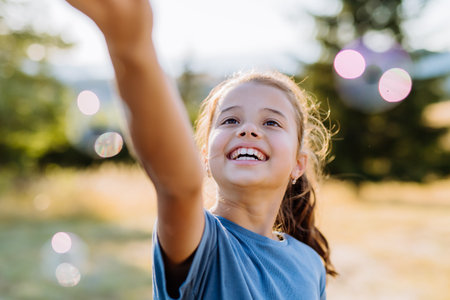 Portrait of a beautiful little girl smiling in nature, with bubbles in the background.の写真素材