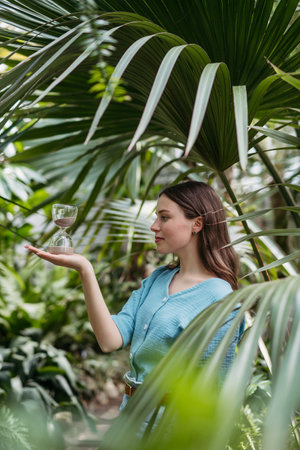 Young woman with hourglass in jungle, concept of nature protection.