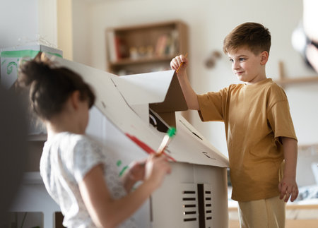 Happy children painting handmade carboard house together.の写真素材