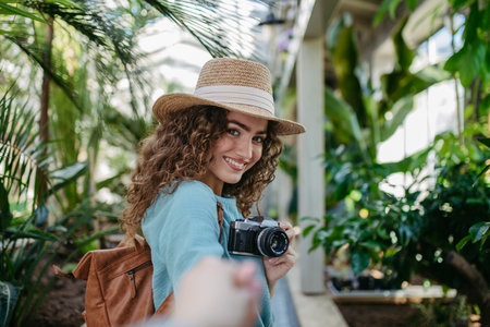 Portrait of young woman with camera in botanical garden.の写真素材