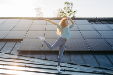 Portrait of young excited woman on roof with solar panels.の写真素材