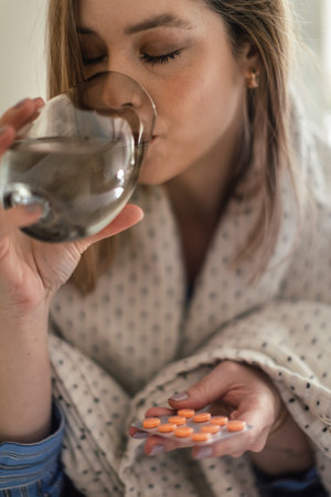 Close up of young woman taking pills.