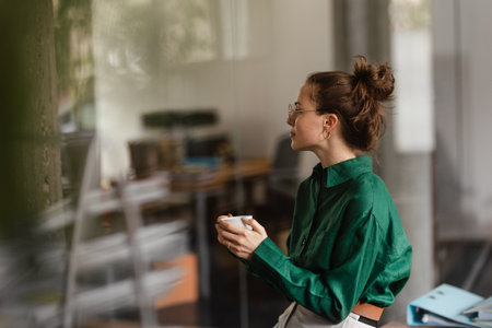 Happy female business owner in her own office drinking coffee.