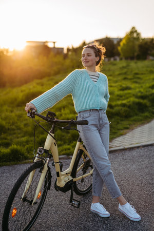 Young woman standing by electro bicycle, concept of commuting and ecologic traveling.の写真素材
