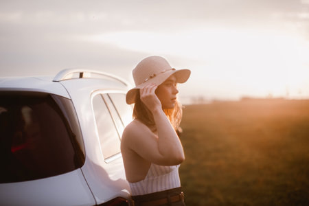 Portrait of young smiling woman standing near her car, enjoying summer time.の写真素材