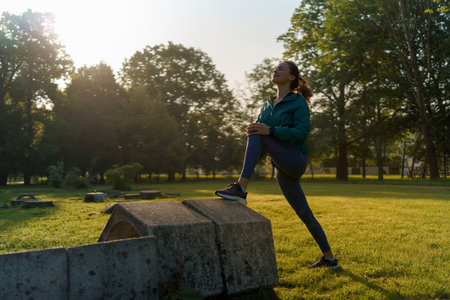 Full lenght portrait of beautiful fitness woman stretching before morning outdoor workout in the city park.の写真素材