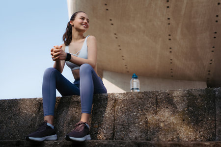 Young fitness woman resting after workout session on sunny morning.の写真素材