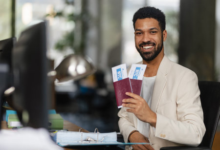 Young happy man holding plane tickets in office.の写真素材