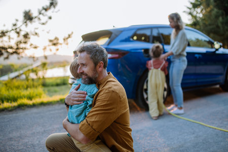 Family with two kids charging their electric car during family trip.の写真素材