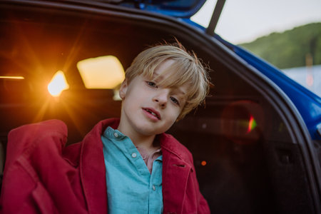Close up of little boy sitting in a car trunk.の写真素材