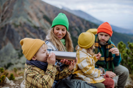 Happy family resting, having snack during hiking together in autumn mountains.