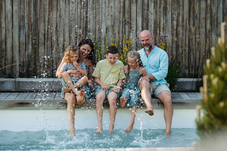 Cheerful family with three kids having fun together sitting by a pool.の写真素材