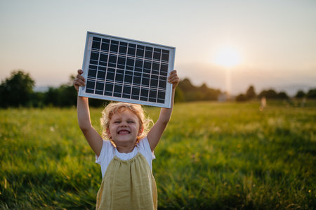 Little girl with model of solar panel, standing in the middle of meadow Concept of renewable resources.の写真素材