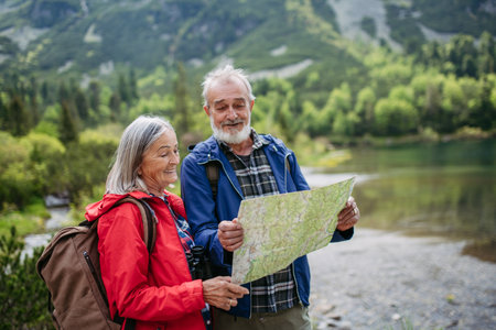 Senior tourists with backpacks reading map, preparing for hike.の写真素材