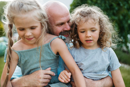 Portrait of father embracing his two beautiful daughters in the garden.の写真素材