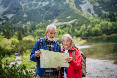 Senior tourists with backpacks reading map, preparing for hike.の写真素材