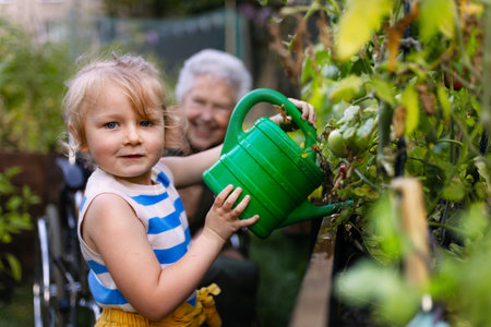 Portrait of a little adorable girl helping her grandmother in the garden.の写真素材