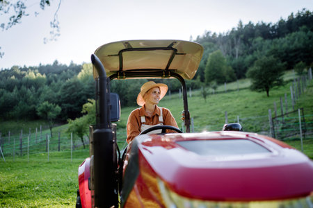 Progressive female farmer driving tractor on her own farm.