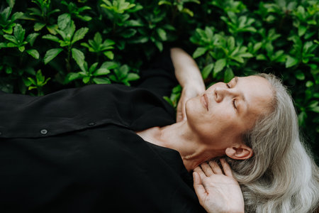 Portrait of a beautiful woman with gray hair lying on her back with hands behind head.の写真素材