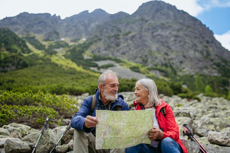 Senior tourists sitting on rocks and looking at the route on a map.の写真素材