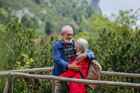 Senior tourists embracing on a wooden bridge during a hike in the autumn mountains.の写真素材