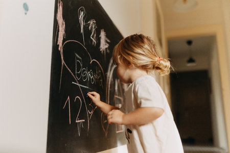 A little girl drawing on a chalkboard with chalk.の写真素材