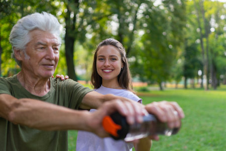 The senior man exercising in the park, using a water bottle as a dumbbell.の写真素材