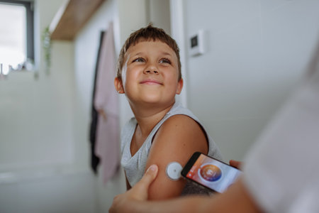 Boy with diabetes checking blood glucose level at home using continuous glucose monitor.の写真素材