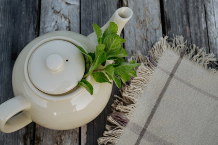 Top view of a teapot with homemade lemon balm tea on a wooden table.の写真素材