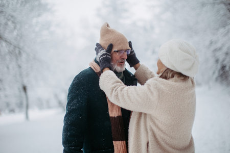 Elegant senior couple walking in the snowy park, during cold winter snowy day.の写真素材
