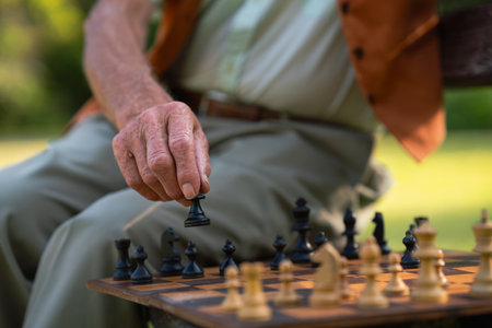Close up of senior man playing chess in a city park.の写真素材