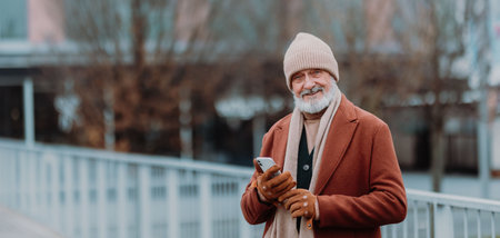 Elegant senior man walking near the river, during cold winter day.