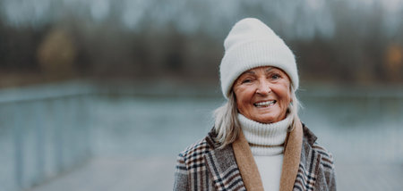 Elegant senior woman walking near the river, during cold winter day.の写真素材