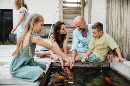 Cheerful family with three kids taking care of fish in pond.の写真素材