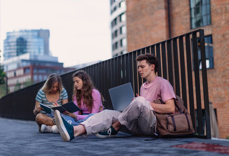 Group of generation Z students studying together outdoors after school.
