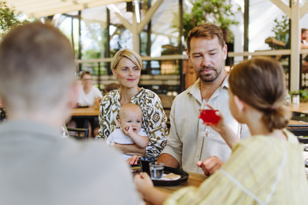 Big family with children and a small baby at family dinner in a restaurant.の写真素材